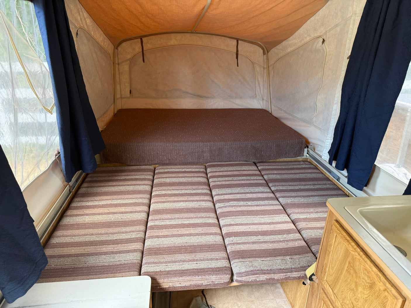 offering a compact living space.|Cozy RV rental pop-up camper interior features a dinette