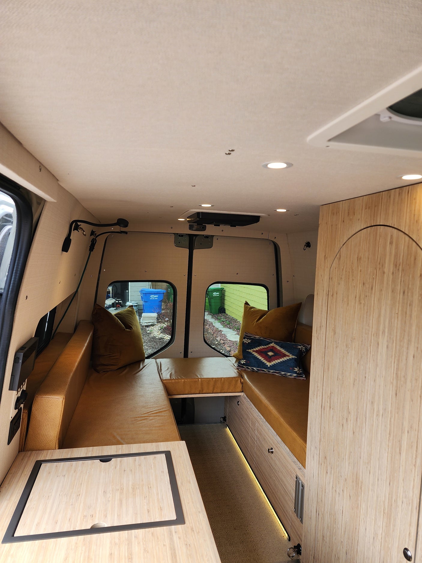 Cozy, modern custom camper van interior perfect for an RV rental adventure, featuring wood accents & comfortable seating.