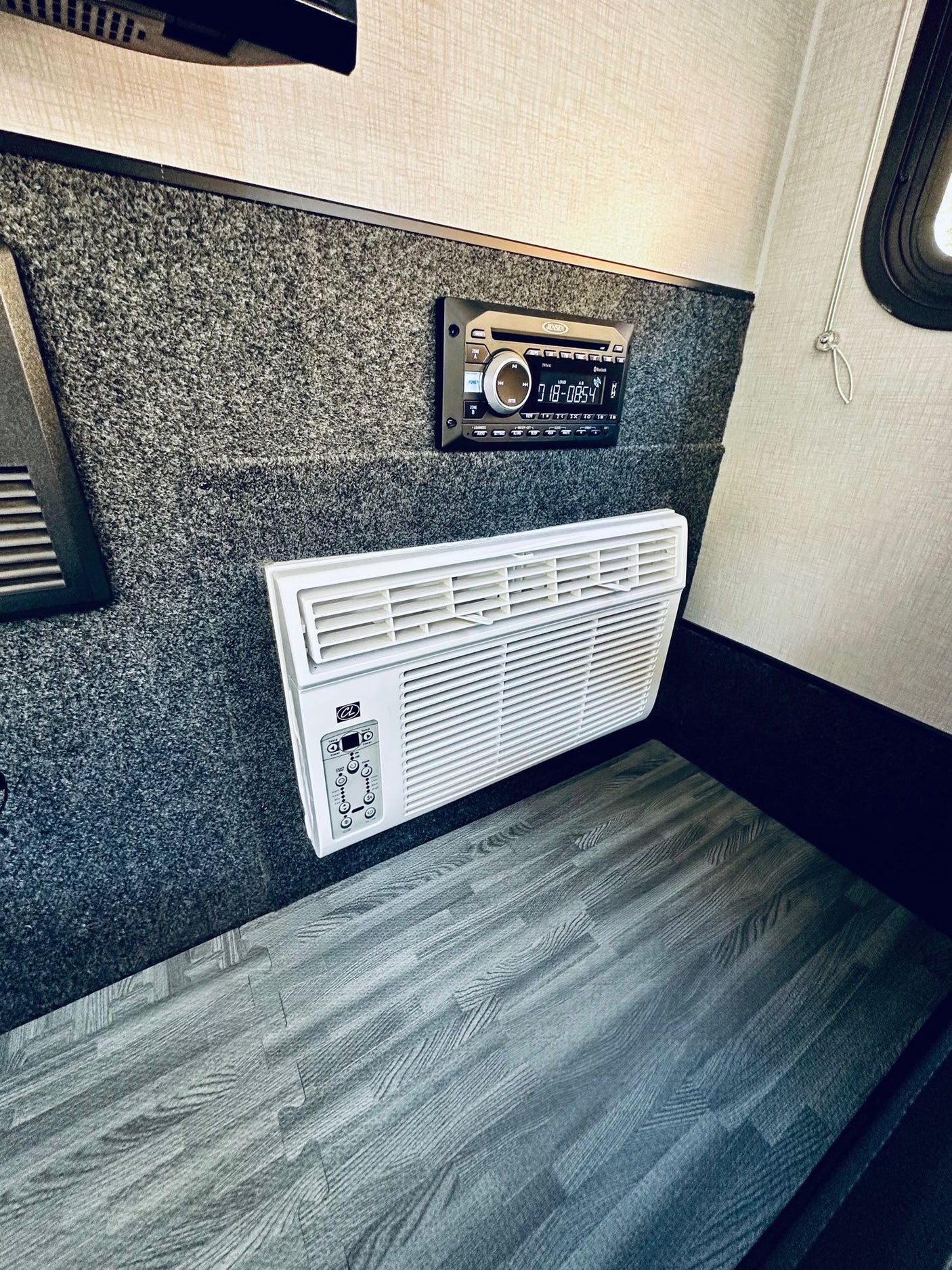 RV rental: Inside, a stereo and AC unit are mounted on carpeted walls above wood-look flooring.