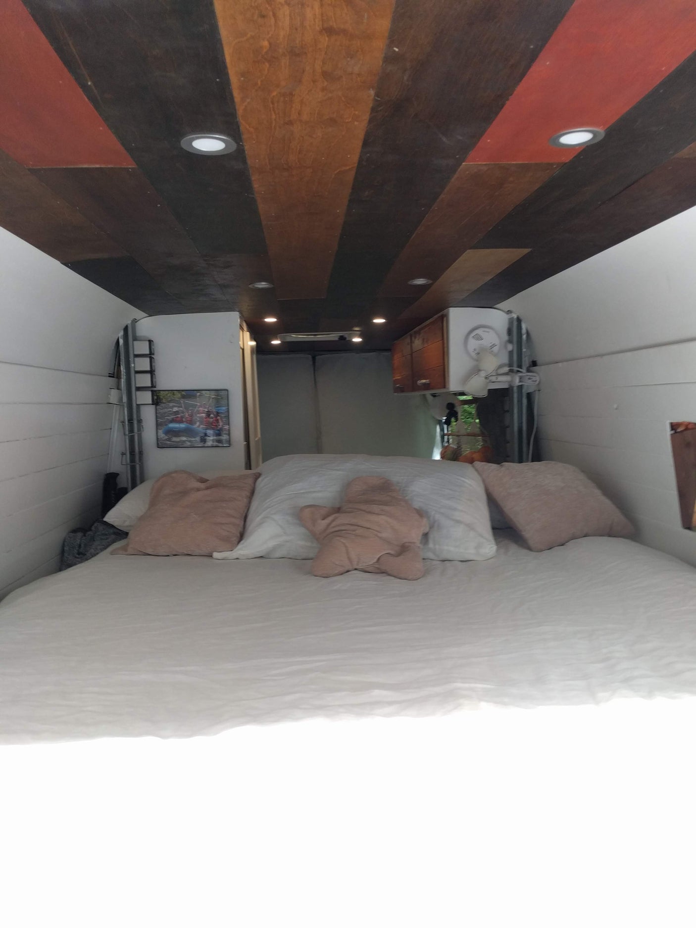 Step into this cozy RV rental camper van, featuring a comfy bed, unique wood ceiling, & smart lighting for travel.