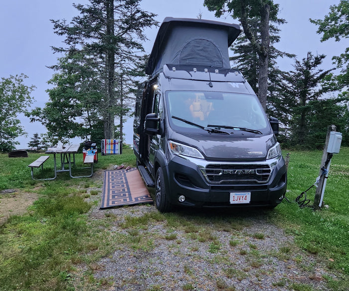 and nature views.|Gray RV rental with pop-top extended at a scenic campsite