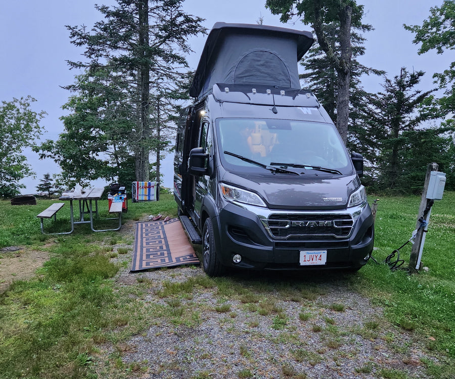 and nature views.|Gray RV rental with pop-top extended at a scenic campsite