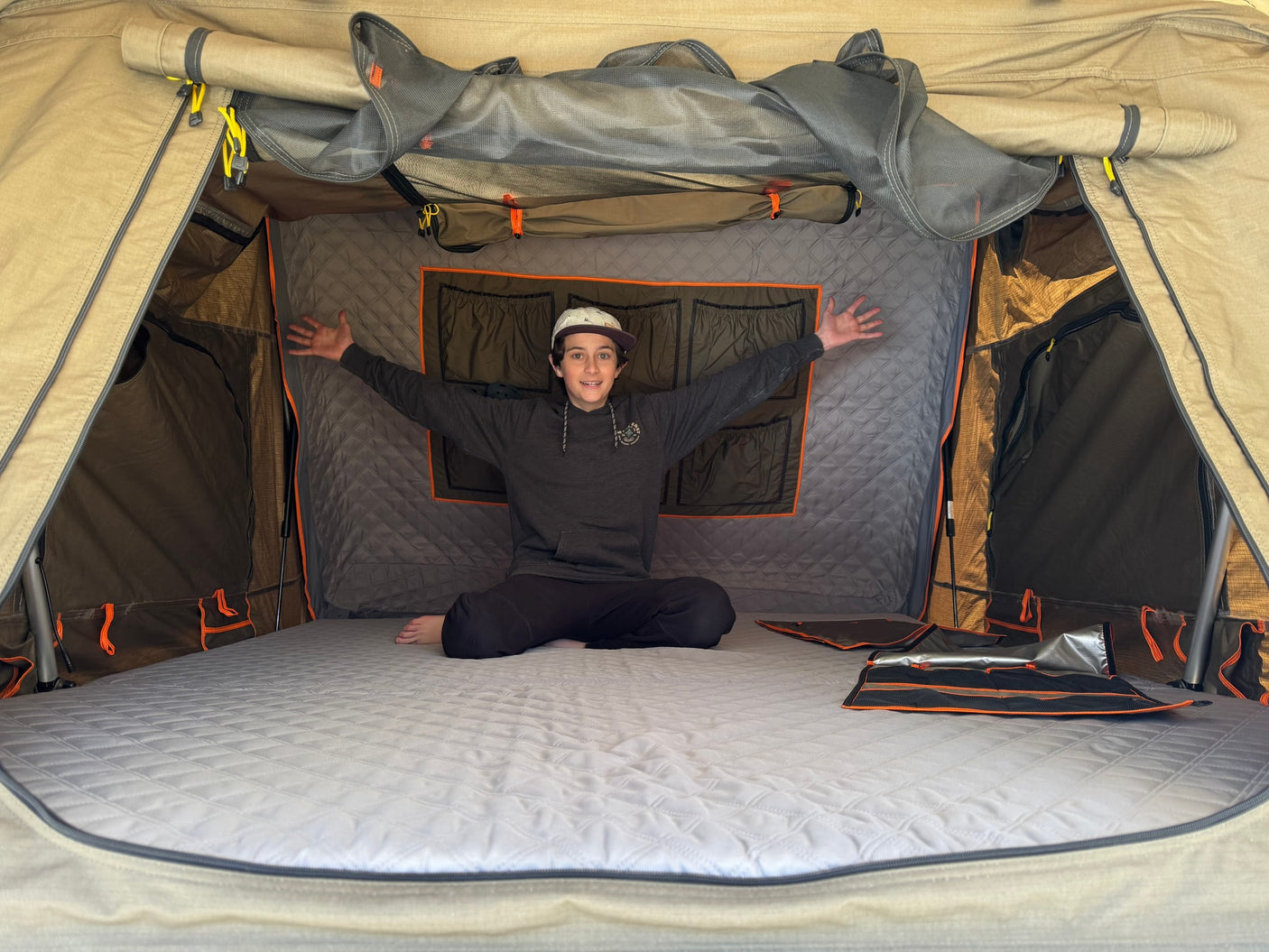 Happy youth in RV rental rooftop tent. See its comfy mattress, storage pockets & mesh windows, great for travel & camping!