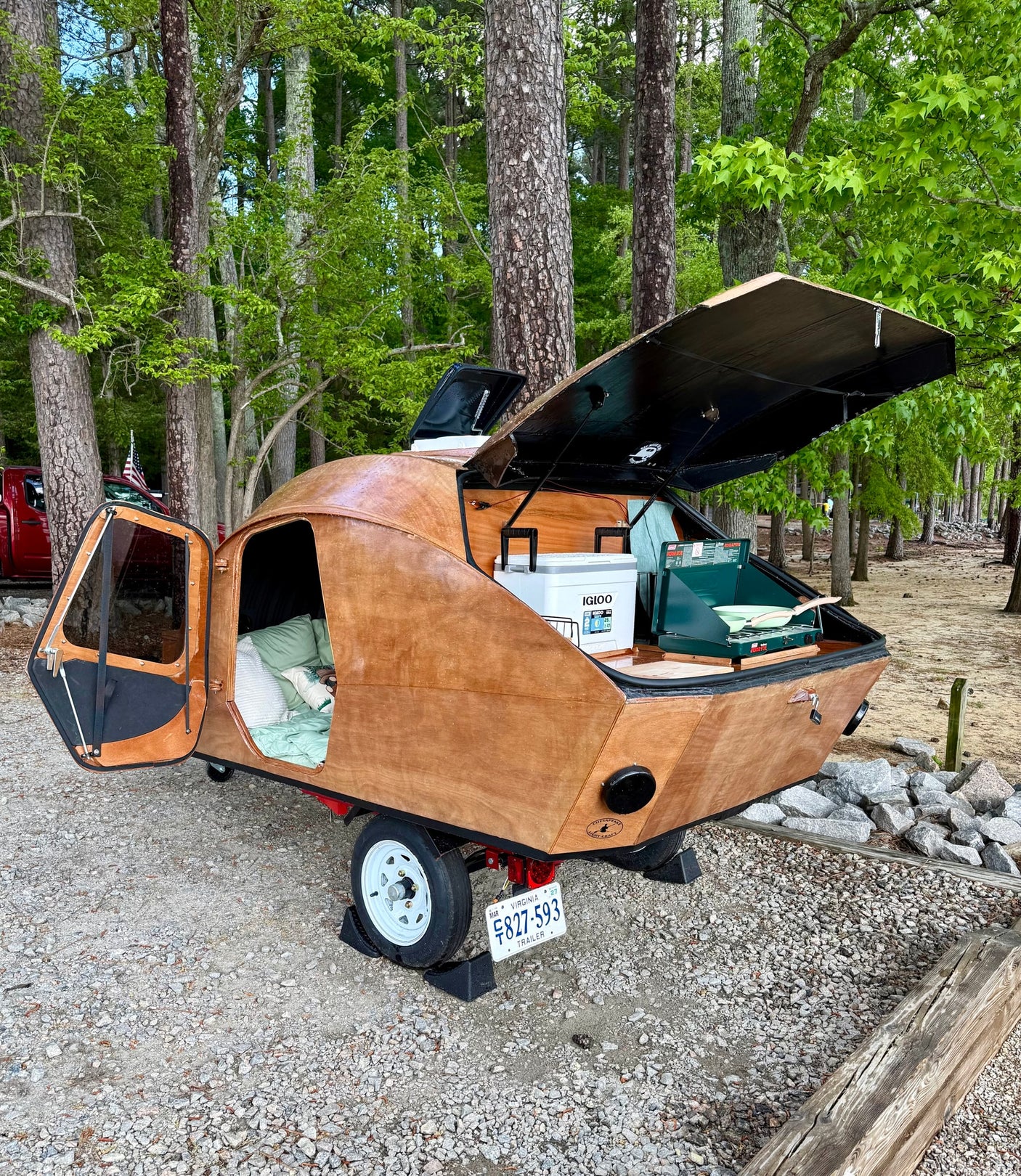 compact alternative to an RV rental for camping.|Unique wooden teardrop RV rental with open rear kitchen & cozy interior. Perfect for camping in this Virginia wooded site.|Inside a cozy RV rental