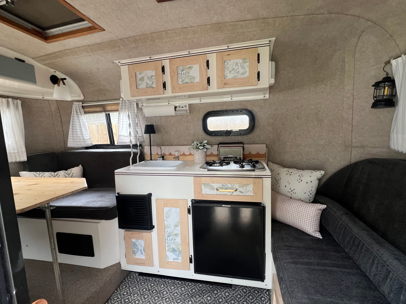 Inside an inviting RV rental, showing a well-equipped kitchenette with sink and stove, dining table, and sofa for cozy camper living. — photo 3