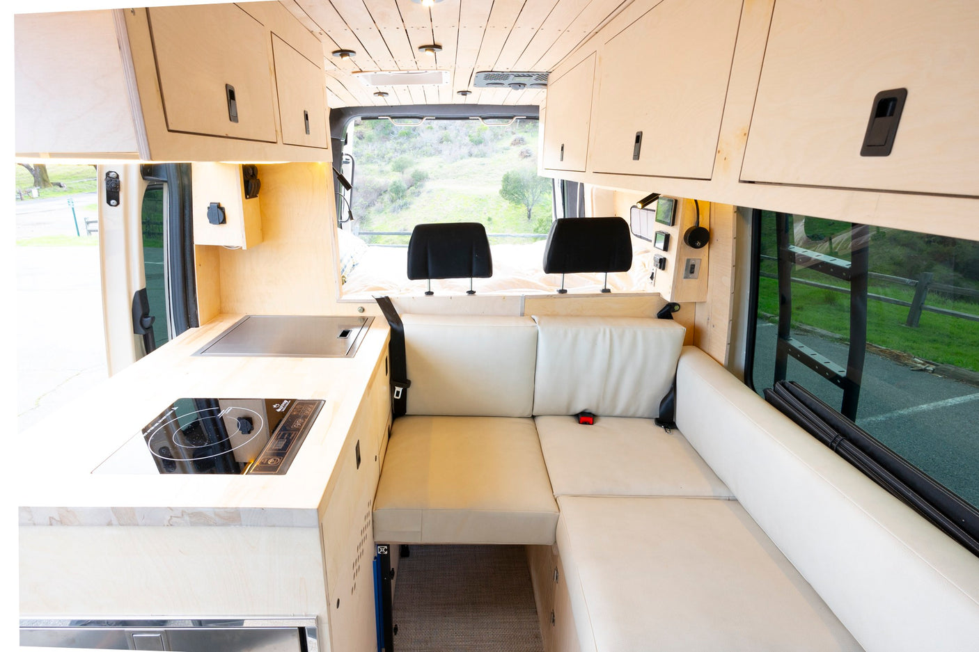 This cozy RV rental interior features a modern kitchenette, comfortable L-shaped seating, and smart overhead storage.