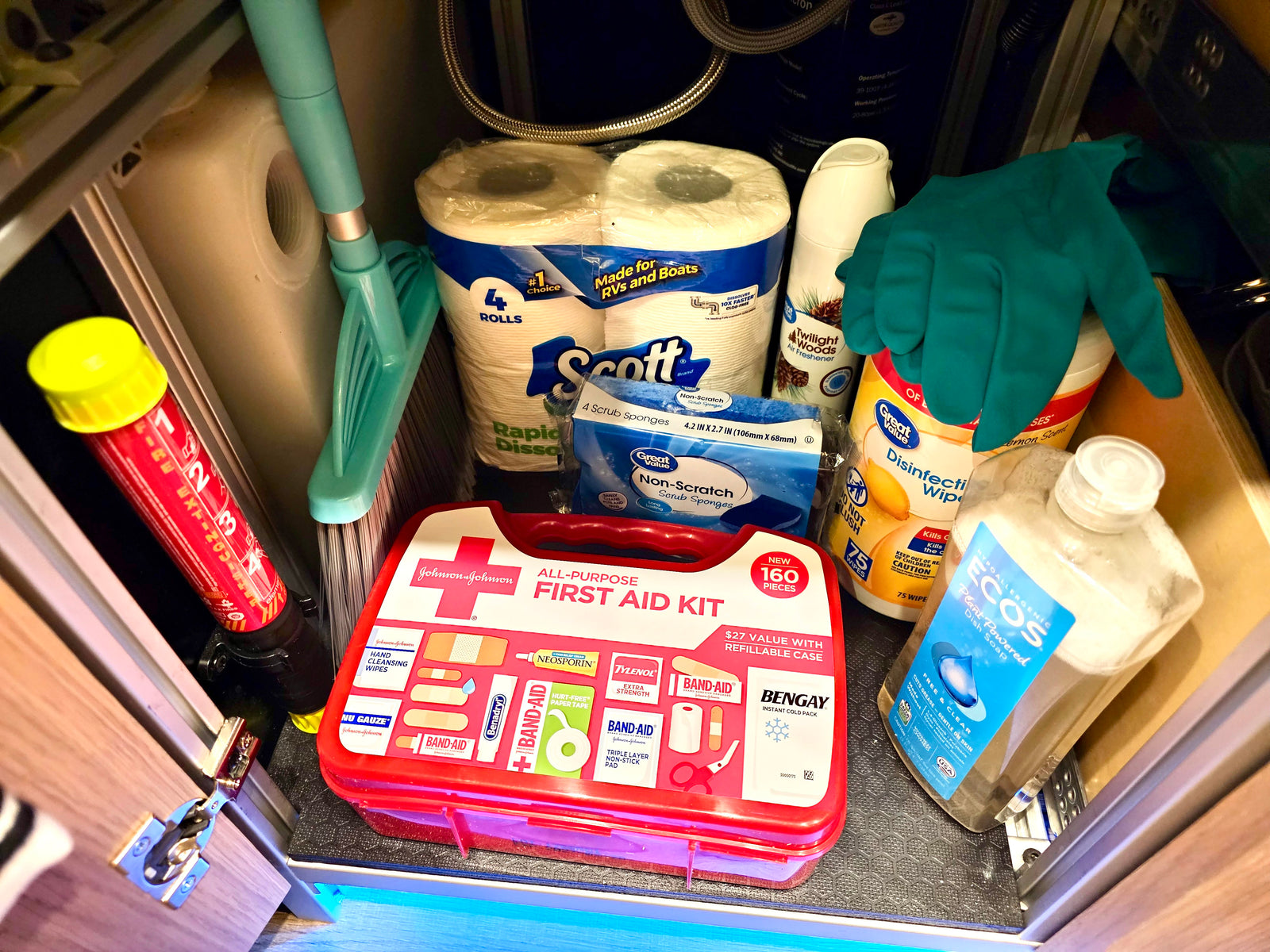 Compact RV rental storage: first aid kit, fire extinguisher, cleaning supplies, and RV-specific toilet paper for travel.