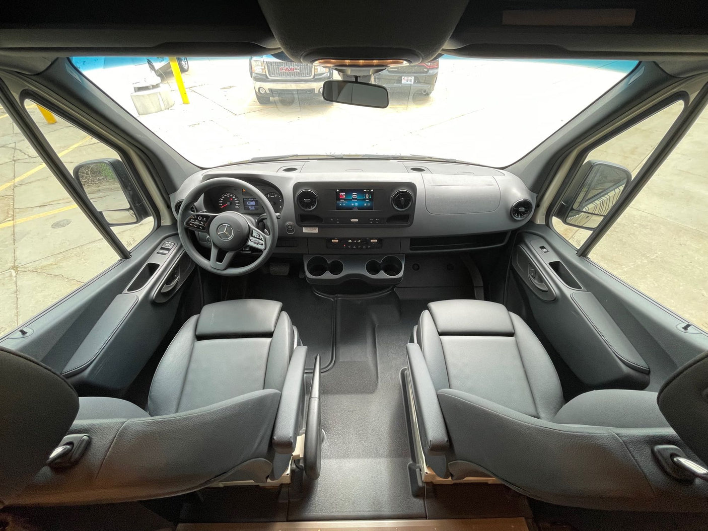 Get ready for your RV rental trip! This spacious van's driver's cabin shows the dashboard, steering wheel, and front seats.