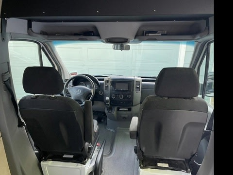 Inside an RV rental, showing the spacious front cabin with driver and passenger seats, dashboard, and overhead storage.