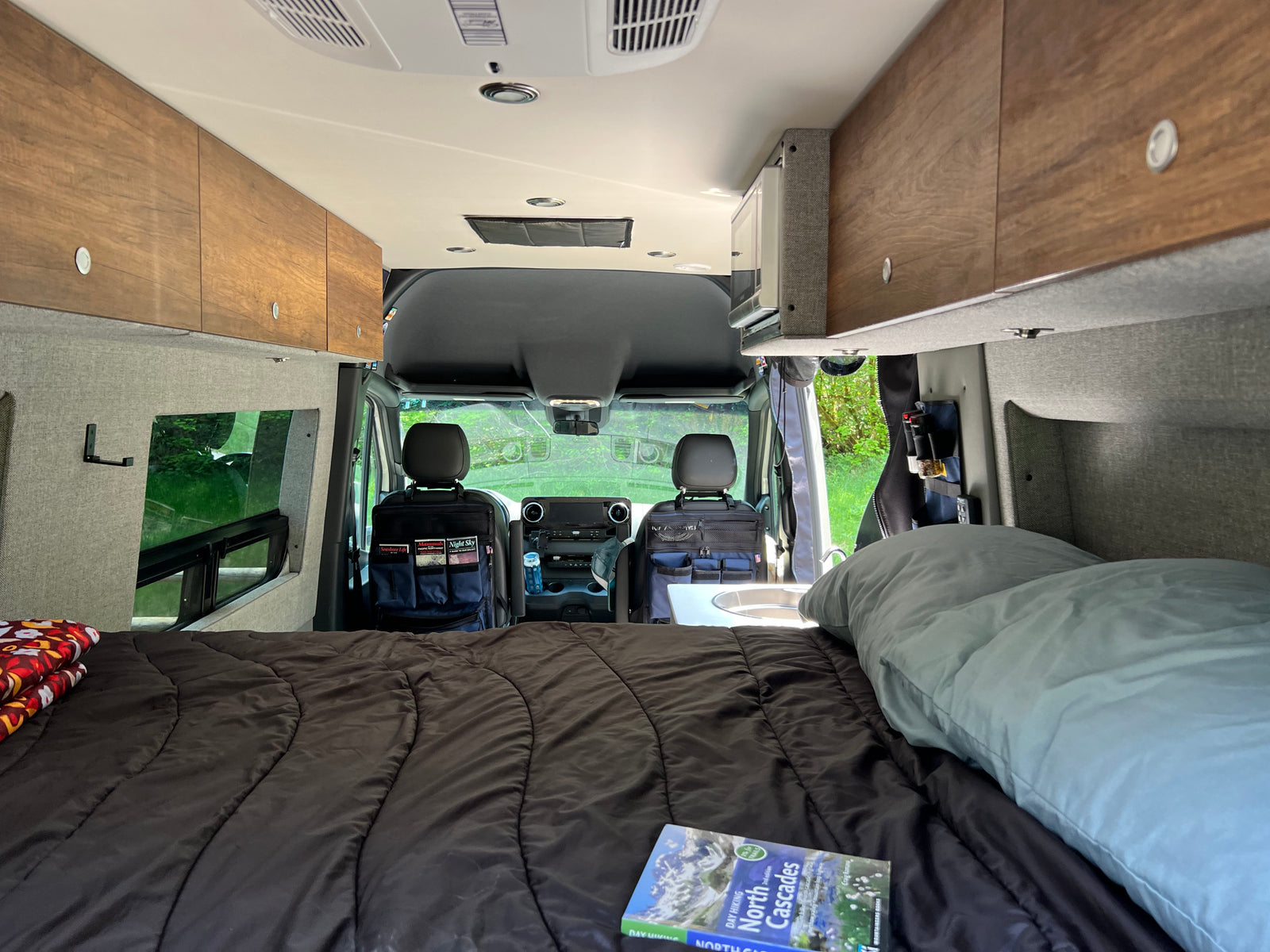 Inside an RV rental: a comfortable bed, compact kitchen area, and ample storage, ready for exploring the scenic outdoors.