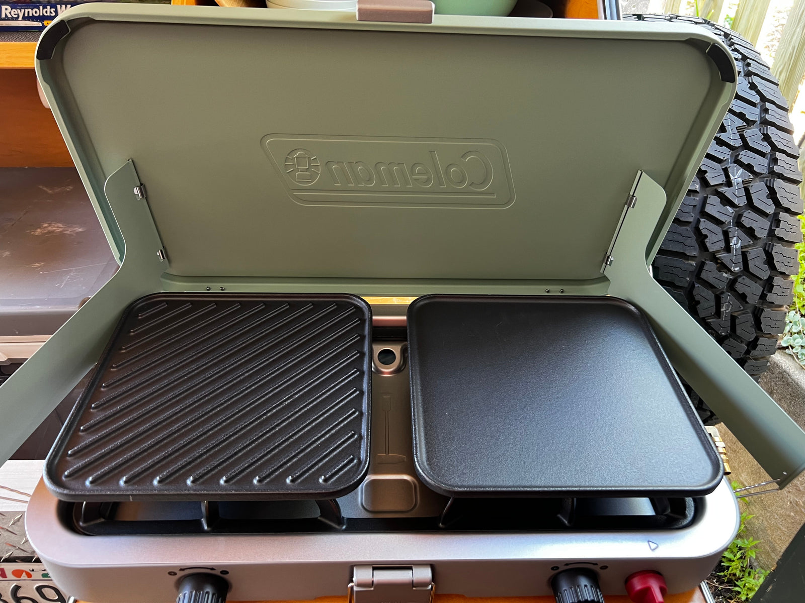 Essential for your RV rental adventure: A Coleman portable grill with griddle and grill plates for campsite cooking.