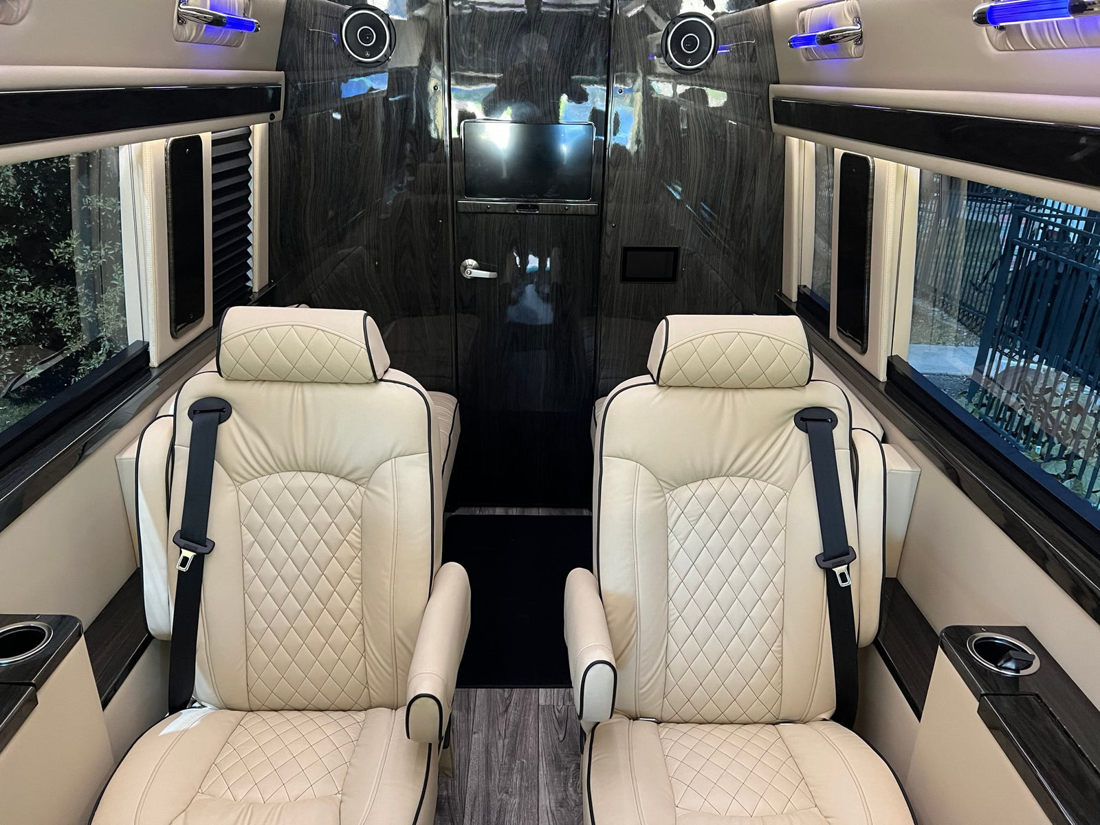 RV rental's luxurious interior with quilted cream leather seats, entertainment display, and sleek wood finishes.