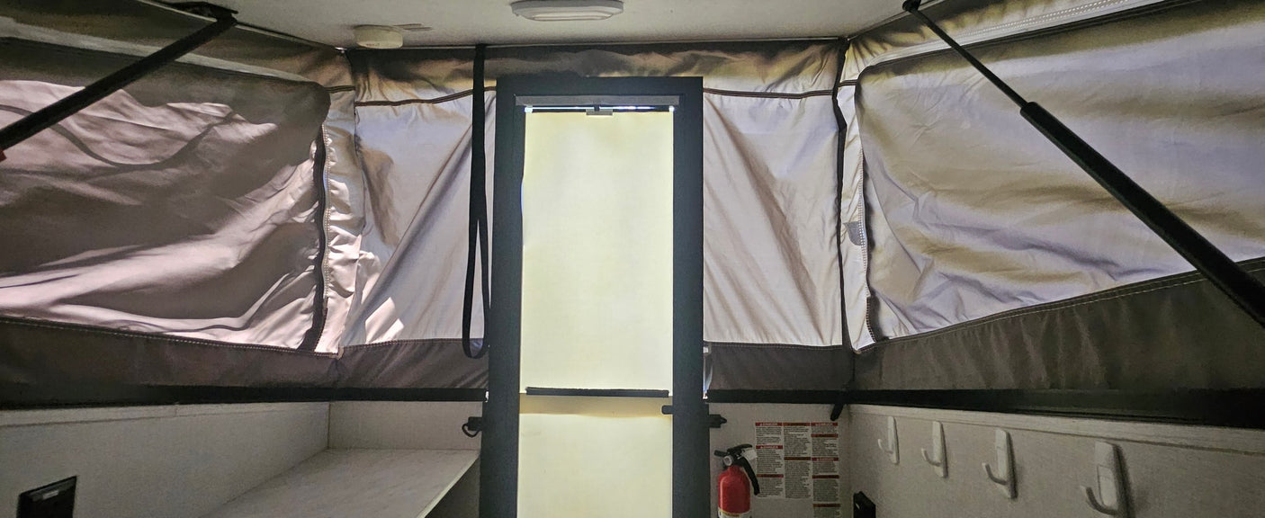 Inside an rv rental pop-up camper: fabric walls, support rods, fire extinguisher, and hooks. Compact interior for your journey.