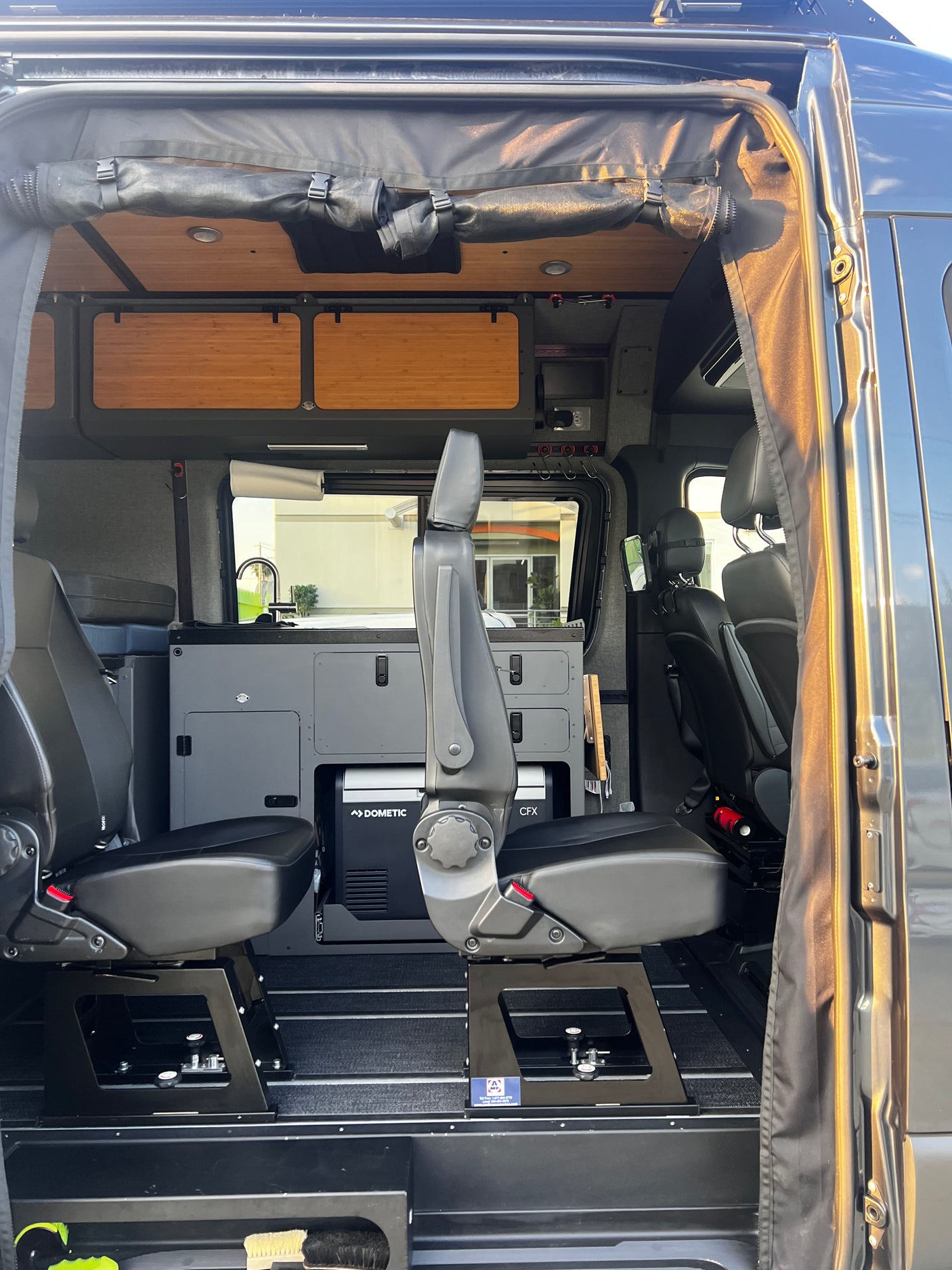 Modern RV rental interior: flexible seating, Dometic cooler, and modular storage in this custom camper van.