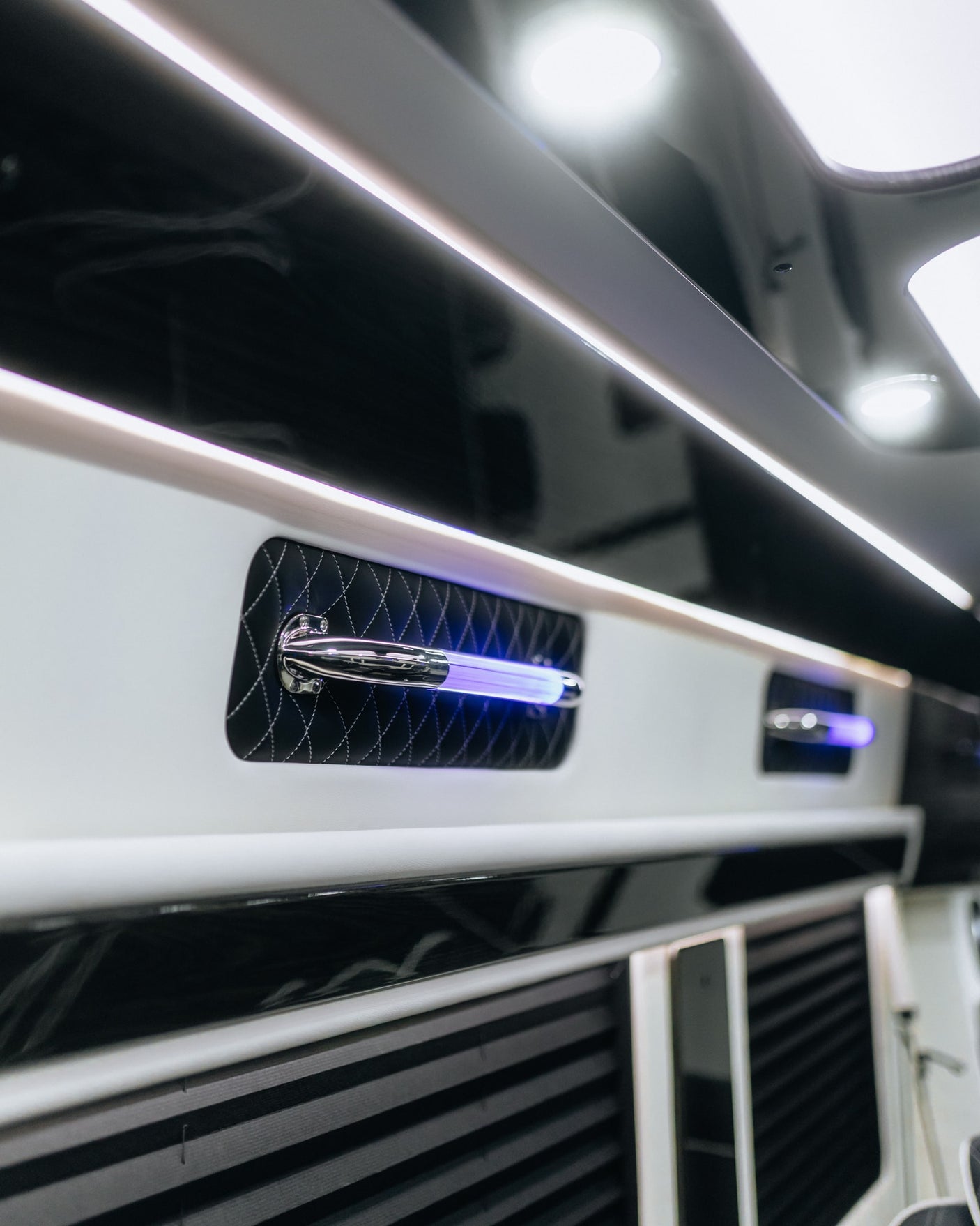 Luxury RV rental interior with modern black & white design, ambient LED strips, and striking blue light feature on quilted panel.
