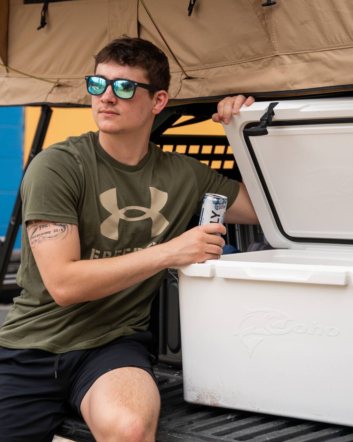and a cooler. Great for an RV rental getaway!|A man with sunglasses enjoys a cold drink from a cooler under a tent