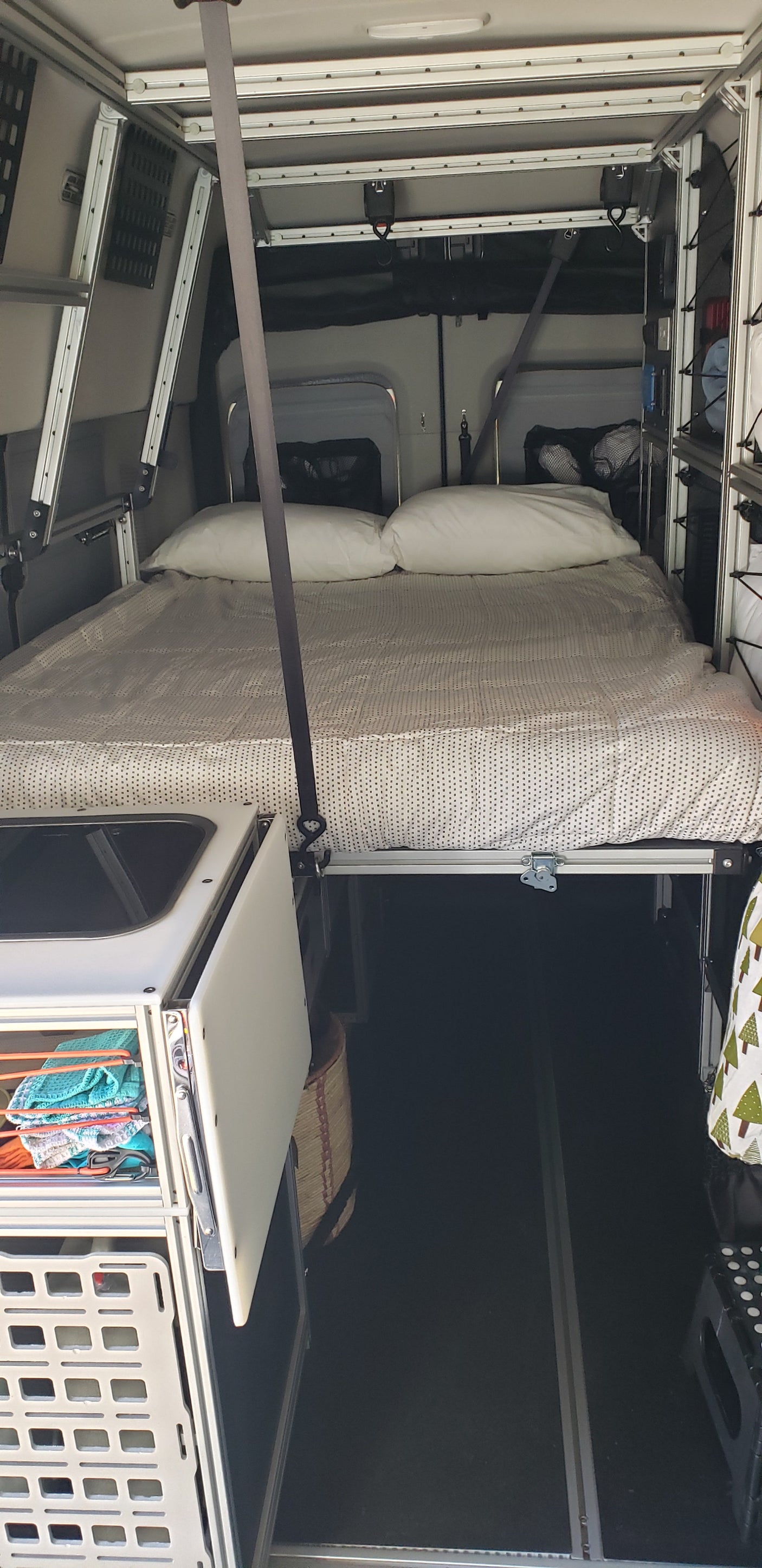 This RV rental showcases a modular camper van interior with an elevated bed, storage units, and open floor space below.