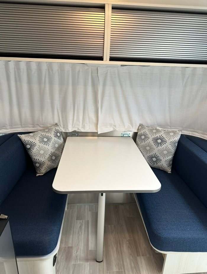 and entertainment system.|Inside a comfy RV rental: a bright sleeping area with a light grey bed