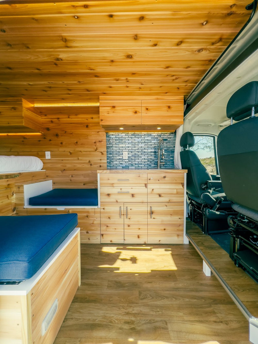 opening to a desert road and mountains. Ideal for road trips.|RV rental: Explore this custom van conversion! Wood-paneled interior