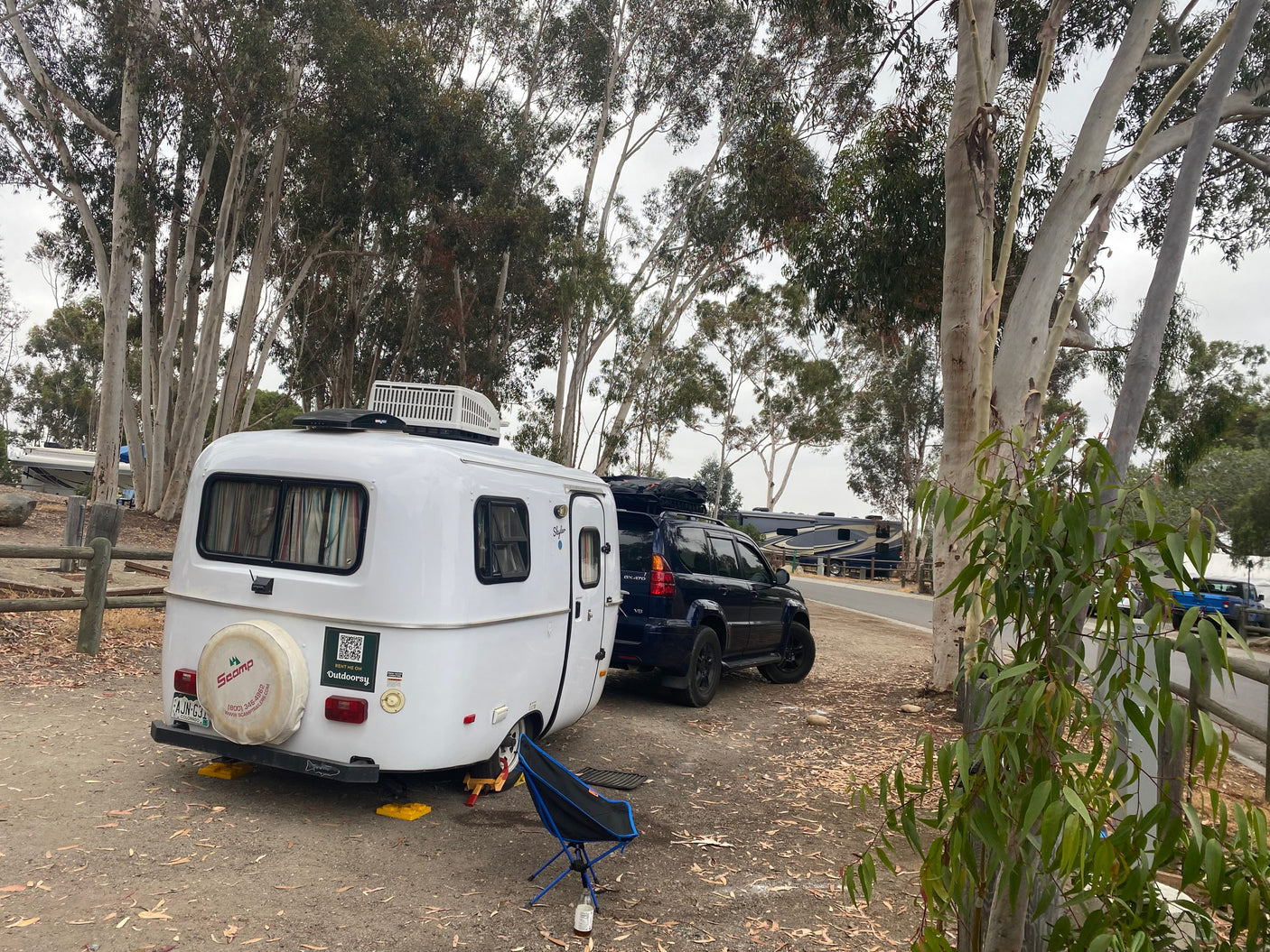 This Scamp travel trailer, an RV rental available through Outdoorsy, is parked with a Lexus GX 470 at a campsite.