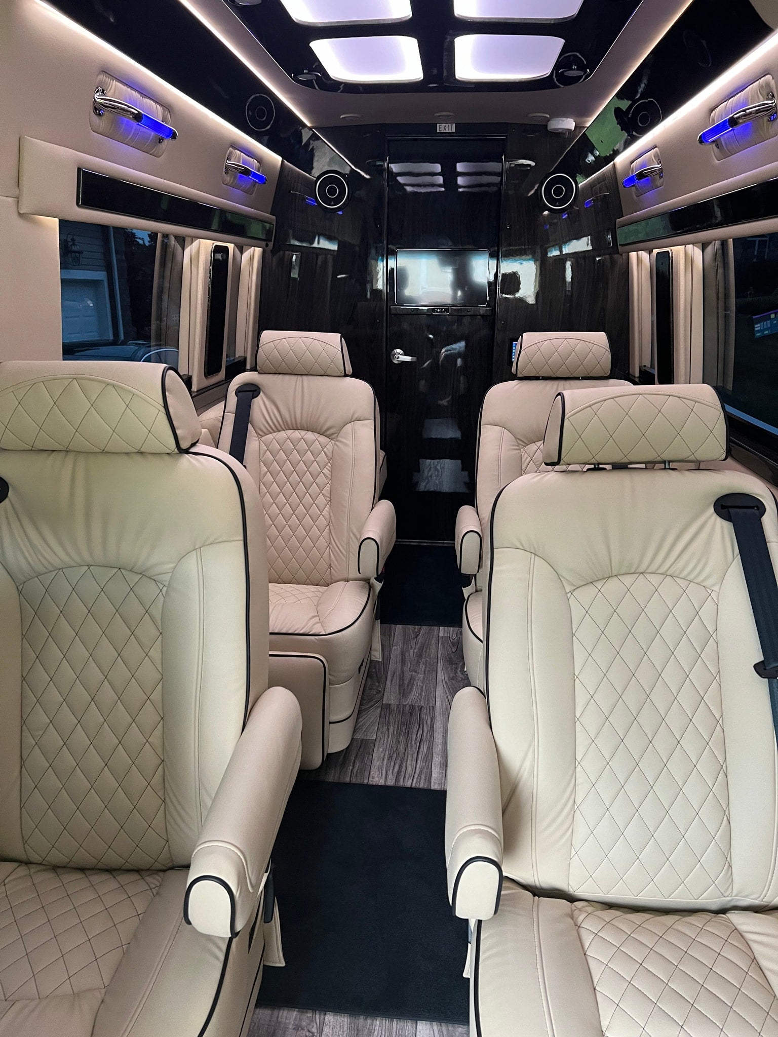 Spacious luxury RV rental interior with cream quilted leather seats, entertainment system, and accent lighting.