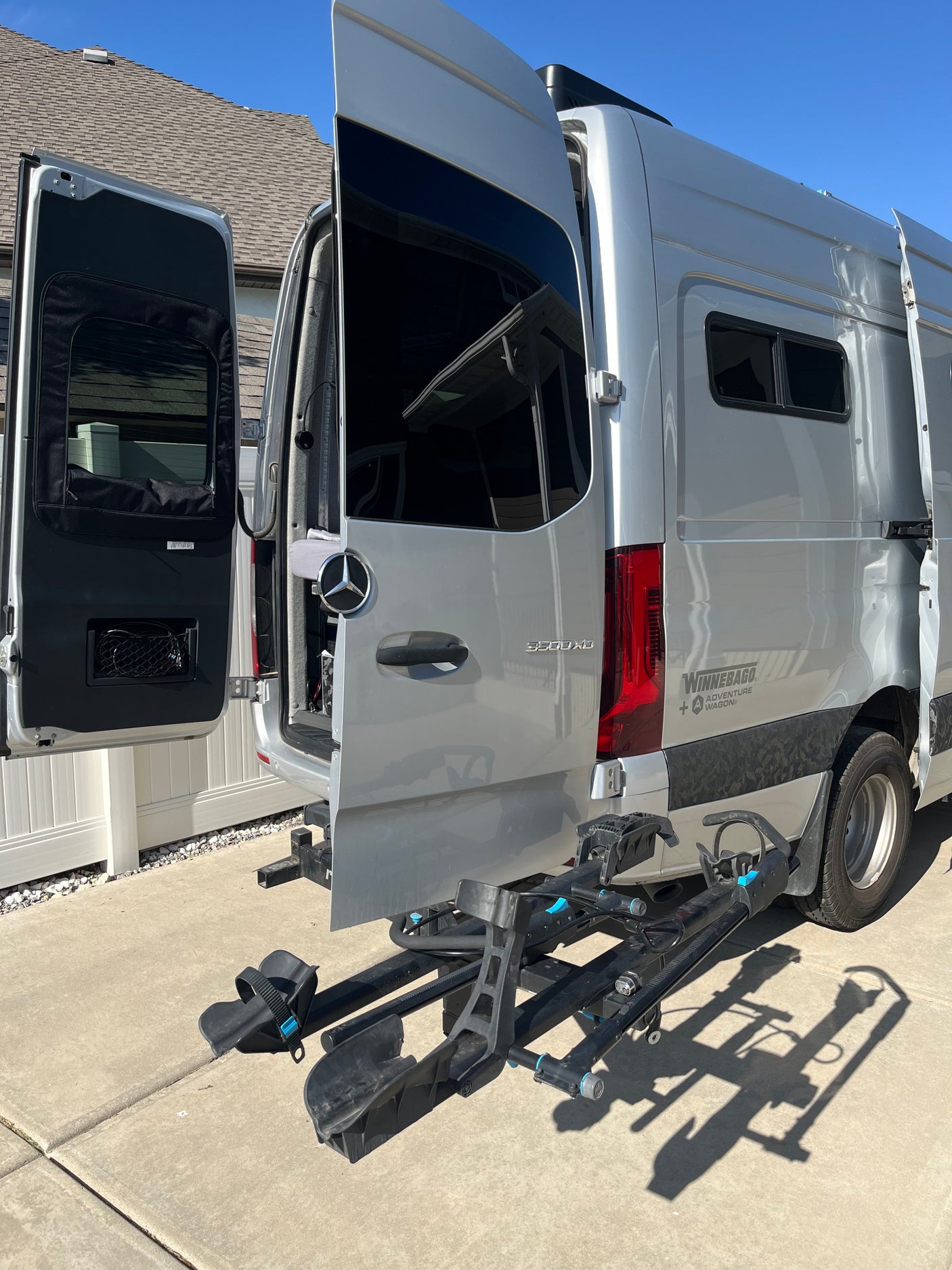Silver Winnebago Sprinter RV rental camper van with open rear doors and a bike rack, ready for adventure.