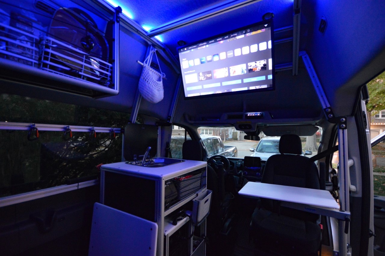 compact space for your next adventure.|Family camping at dusk by an rv rental van. A man tends the campfire while a child watches. Outdoor adventure.|Vibrant custom RV rental