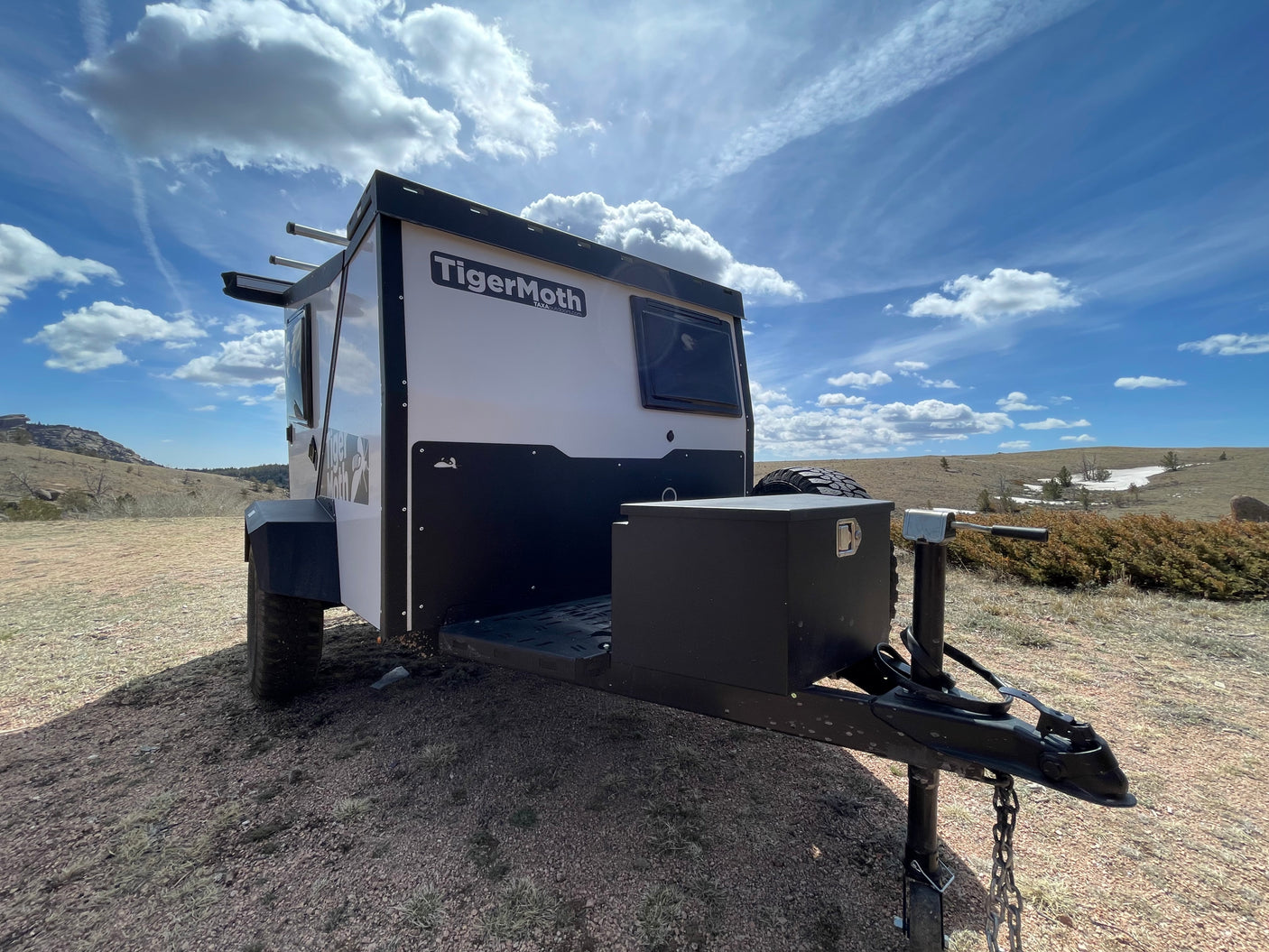 TigerMoth camper trailer, perfect for your next rv rental adventure, parked in a sunny, rugged landscape.