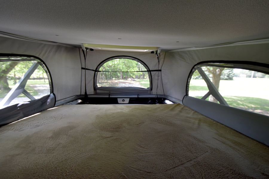 Cozy pop-top bed in an RV rental, offering serene views through mesh windows. Ideal for nature lovers.