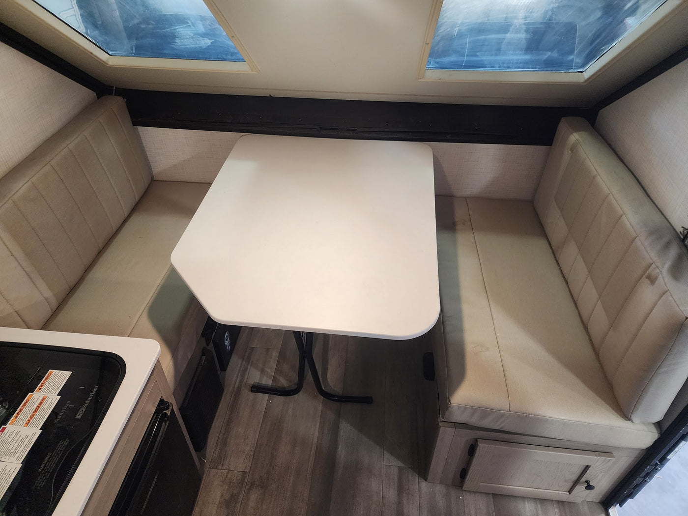 An RV rental's dinette area, showing comfortable benches, a white table, and skylights for a well-lit camper interior. — photo 9