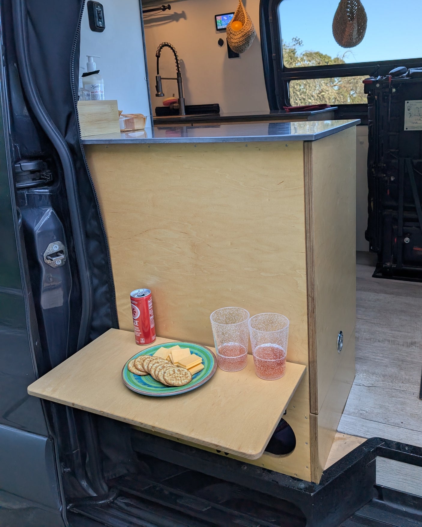 Enjoying snacks inside an RV rental! Van kitchen with a pull-out table, crackers, cheese, and drinks.