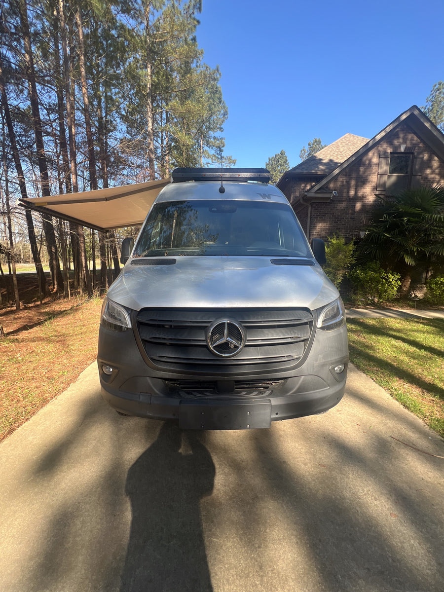 Front view of a silver Mercedes Sprinter RV rental parked on a sunny driveway