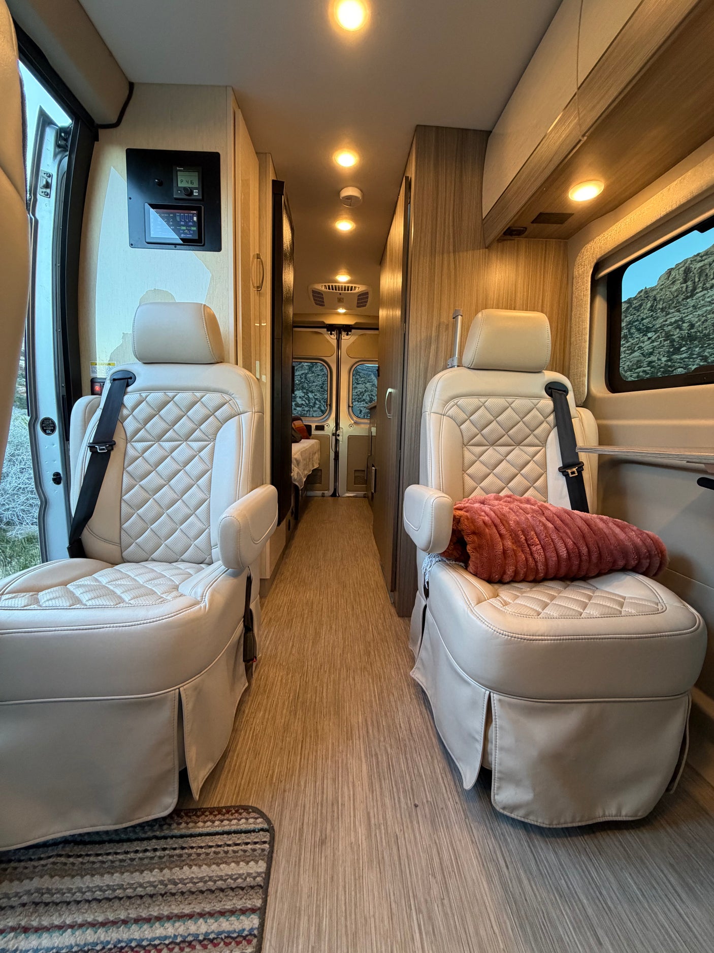 Experience the comfort of this rv rental! Interior features plush, quilted seats, a spacious aisle, and modern controls, ideal for travel.