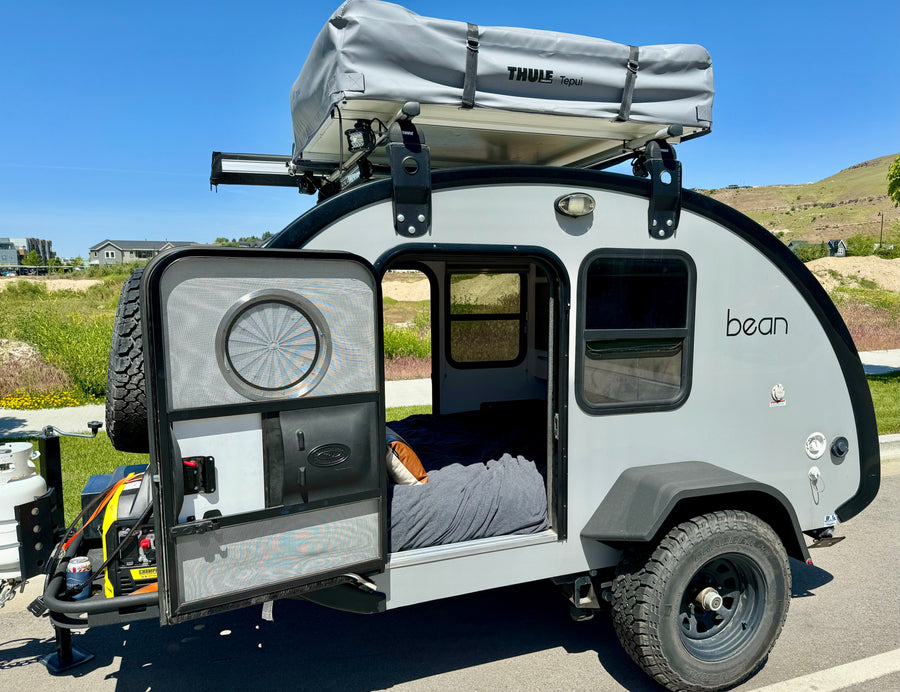 and marshmallows for camping.|Teardrop camper with rooftop tent & awning at a scenic campsite. Ideal for an RV rental adventure!|This RV rental teardrop trailer features a compact outdoor kitchen with a sink