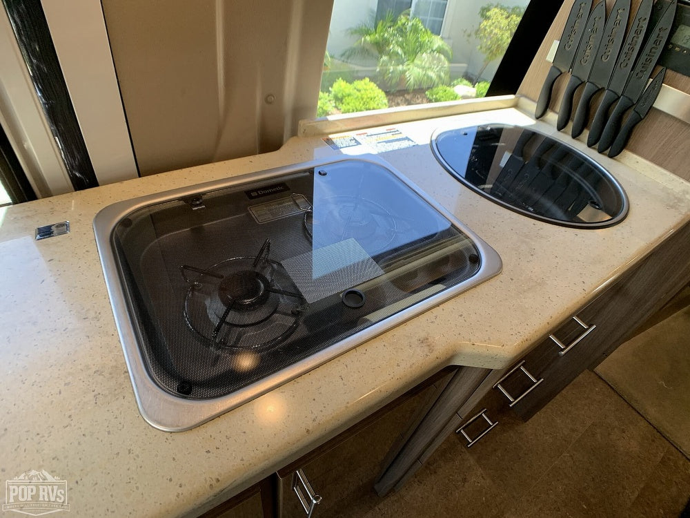 Compact RV rental kitchen features a Dometic cooktop, sink, and ample countertop space for comfortable travel.