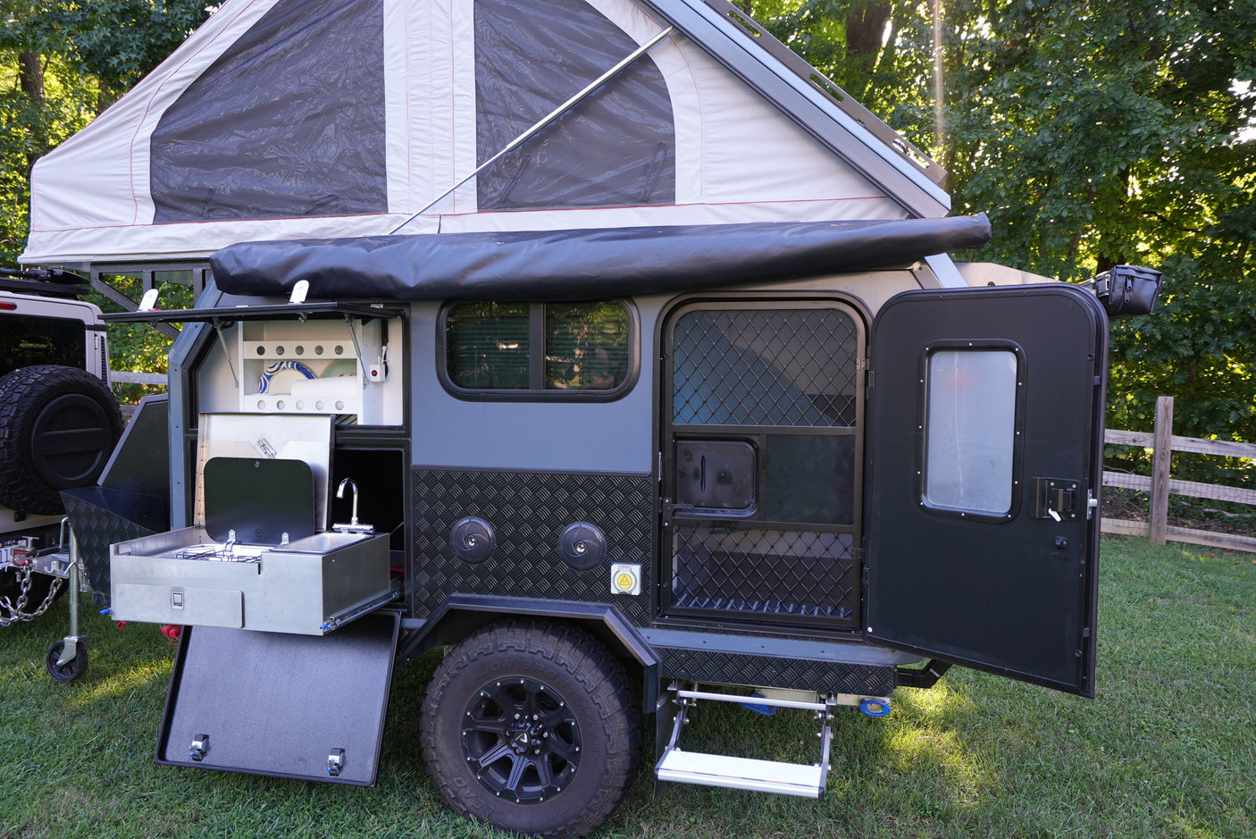 This off-road camper trailer, ideal for an rv rental, features a pop-up tent and a convenient outdoor kitchen for exploring.