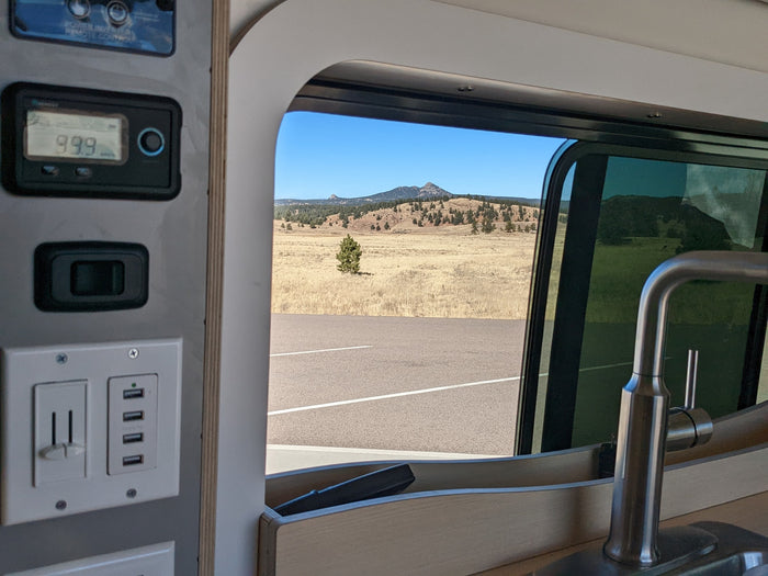 and tree views.|Black RV rental van on a snowy mountain road