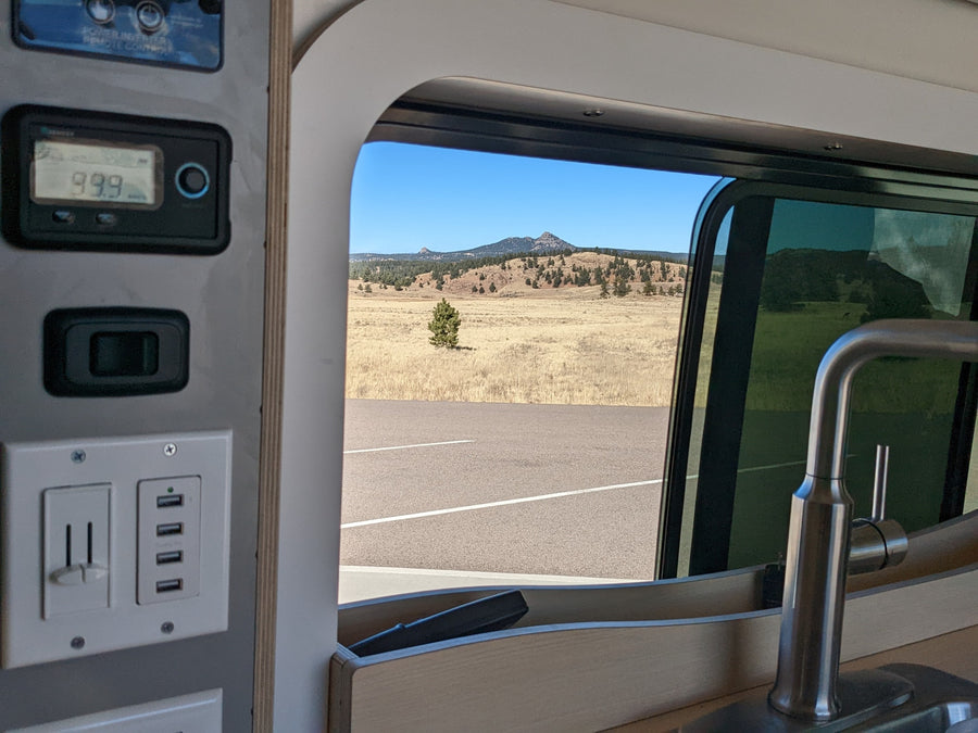 and tree views.|Black RV rental van on a snowy mountain road