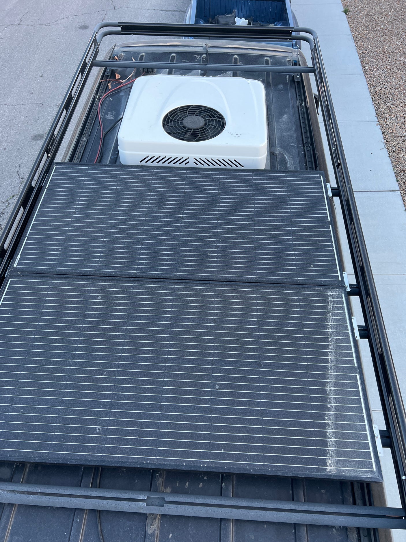 Overhead shot of an RV rental's roof, showing efficient solar panels, an AC unit, and a robust roof rack system.
