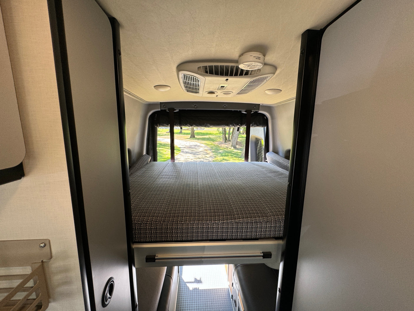 Spacious rv rental interior featuring a comfortable rear bed, AC, and smoke detector. Ready for adventure.
