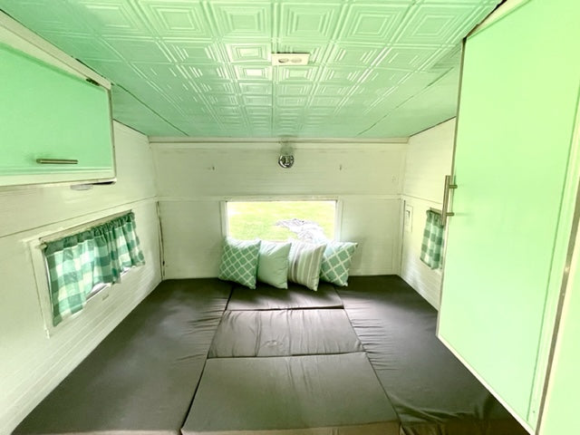 featuring a convertible bed and stylish ceiling tiles.|Cozy RV rental interior: a dinette with a wood table