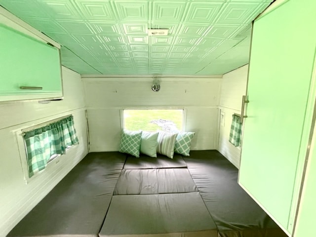 featuring a convertible bed and stylish ceiling tiles.|Cozy RV rental interior: a dinette with a wood table