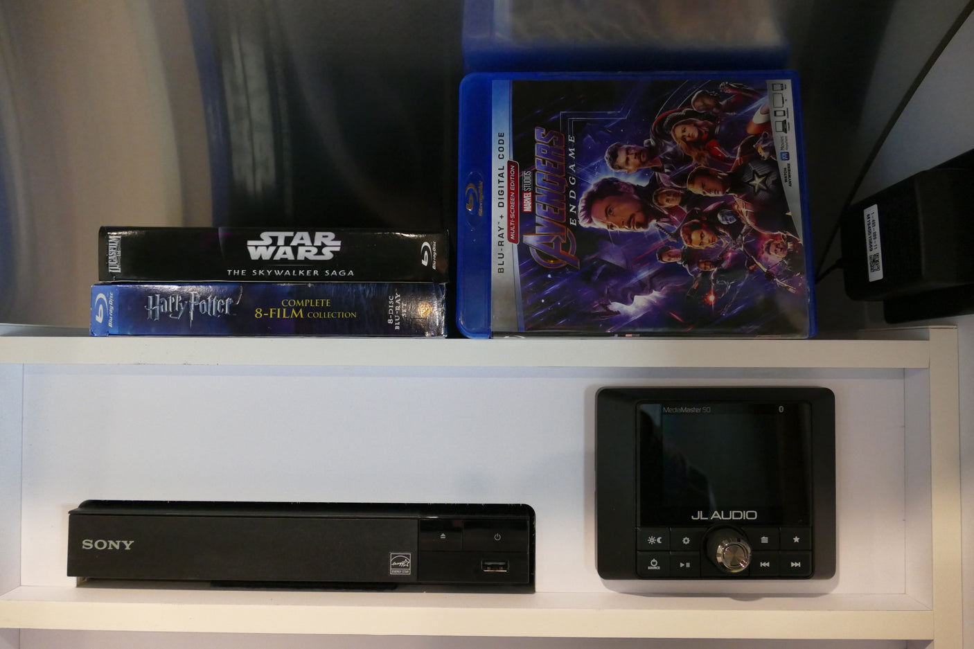 An RV rental's entertainment setup featuring Blu-ray movie collections like Star Wars, Harry Potter, Avengers, with a Sony player and JL Audio receiver.