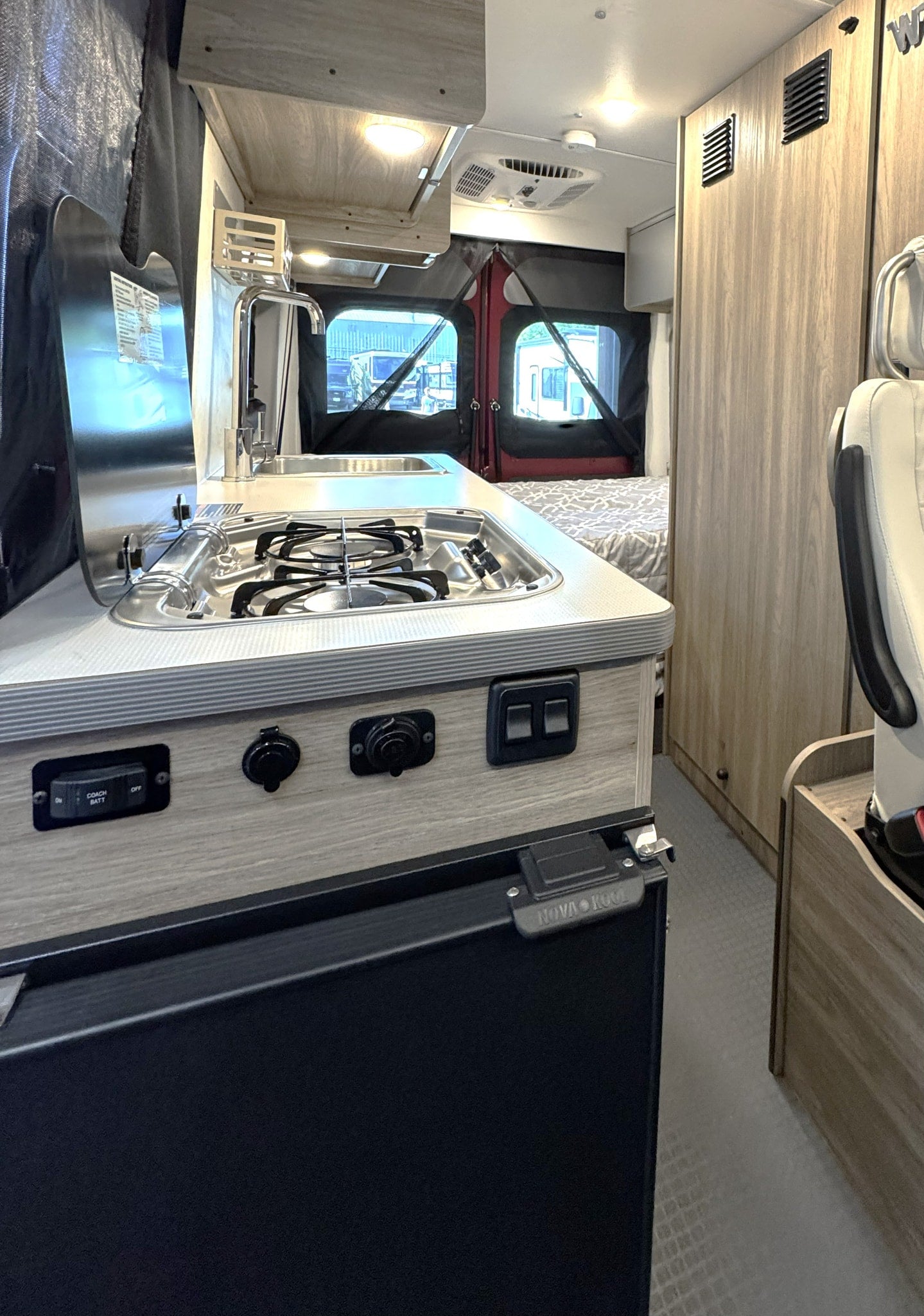 Inside this RV rental: compact kitchen with stove, sink, fridge. Bedroom, controls, and living space for your adventure.
