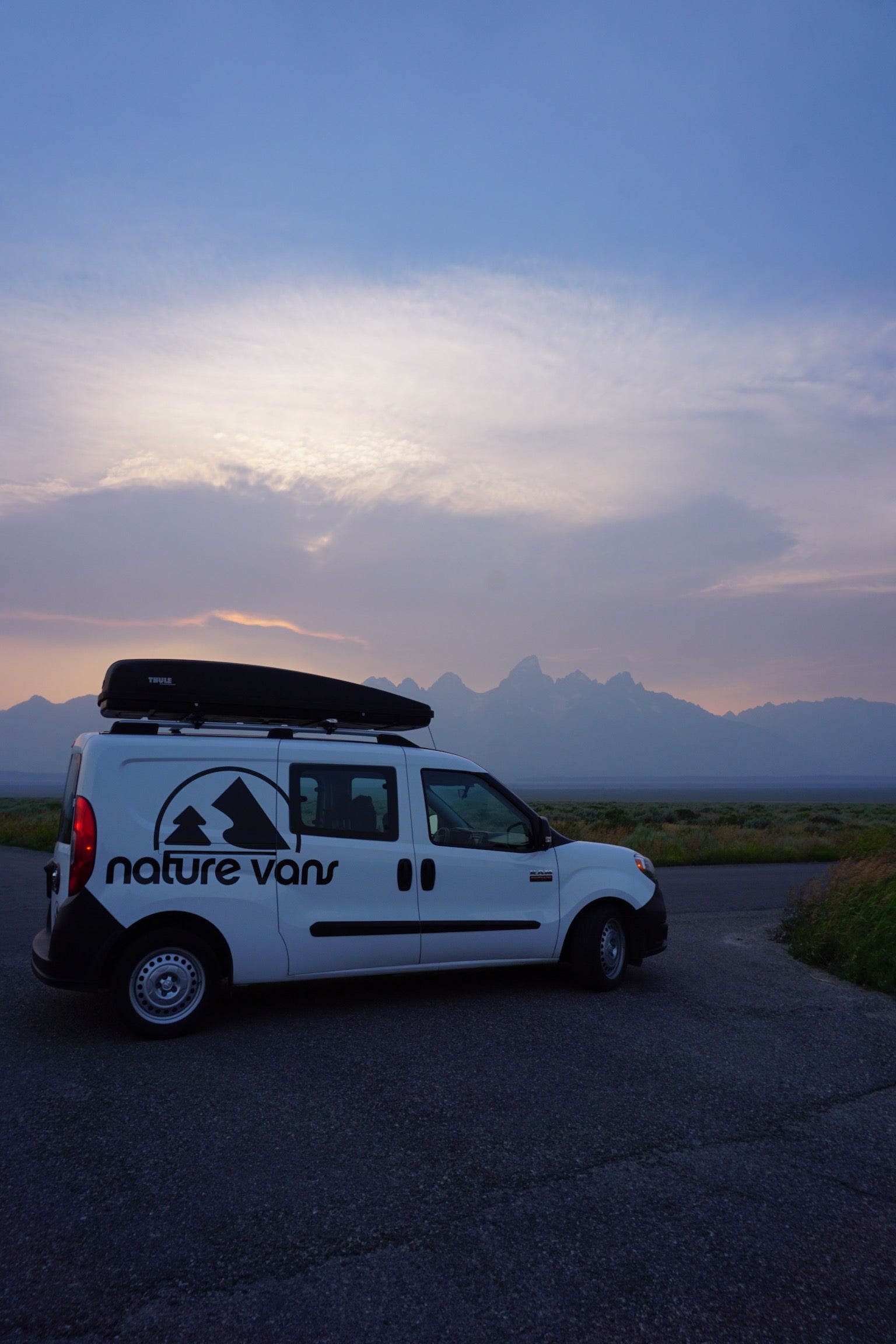 This Nature Vans rv rental van, with a Thule cargo box, is perfectly parked for a mountain sunset view.