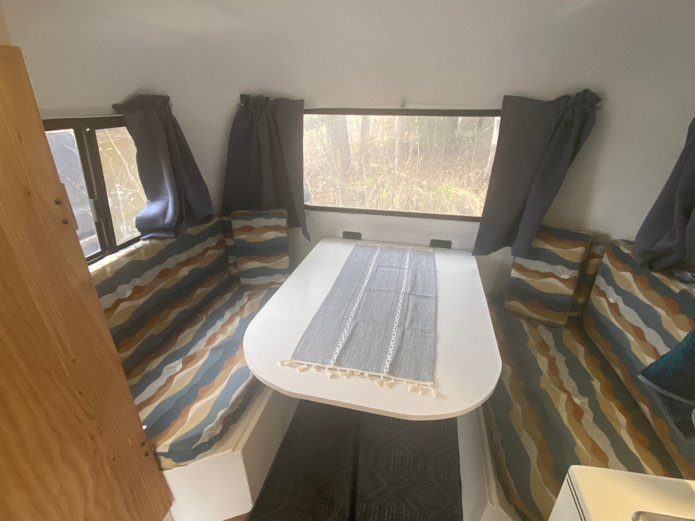 Cozy rv rental interior with a dining table, patterned cushions, and nature views from the windows.