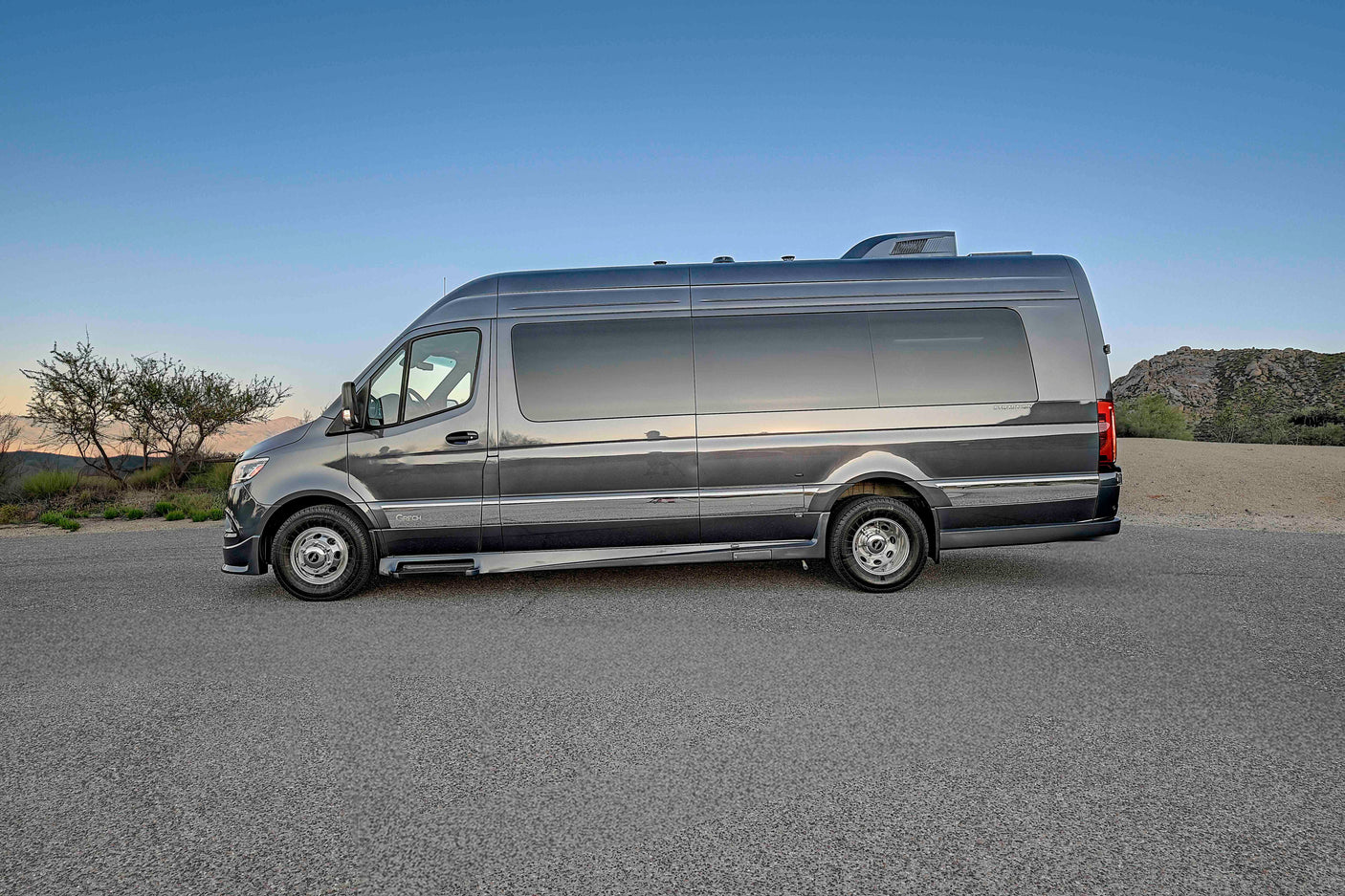 This sleek grey Sprinter camper van rv rental is parked in a scenic desert landscape, perfect for your next adventure.