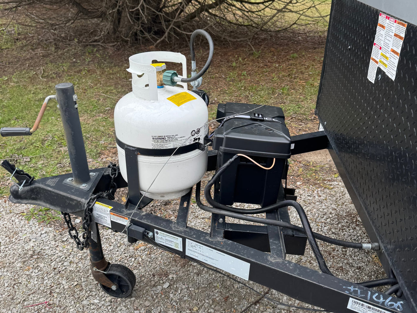 secured on the trailer frame. Provides essential gas for your trip.|RV rental's open exterior storage shows a neatly packed folding table and plastic-wrapped mattress on a laminate floor.|RV rental travel trailer's front area