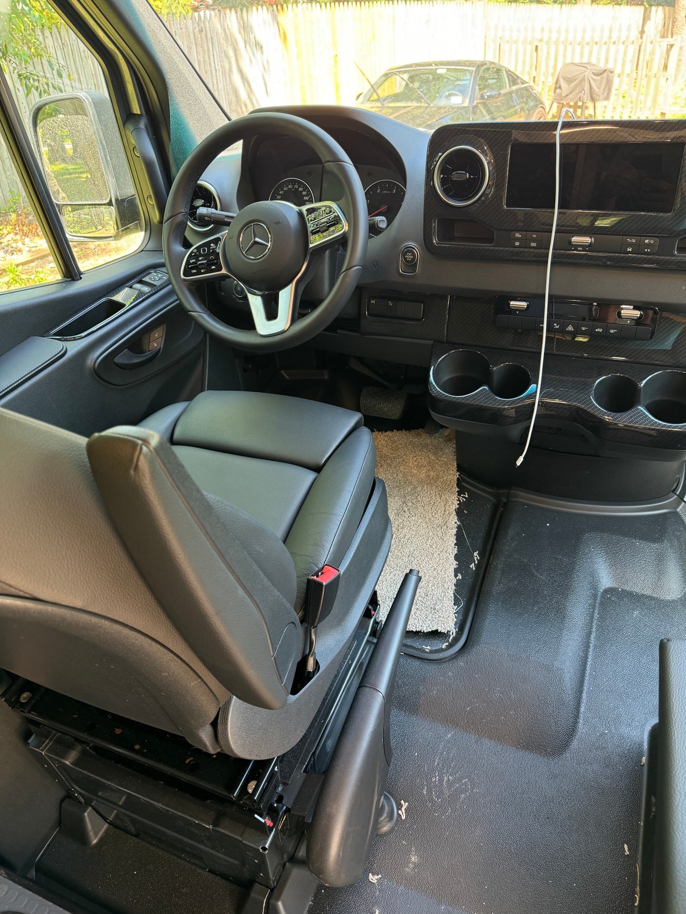 Inside a Mercedes-Benz van RV rental: driver's area featuring a modern dashboard, steering wheel, and black leather seat.