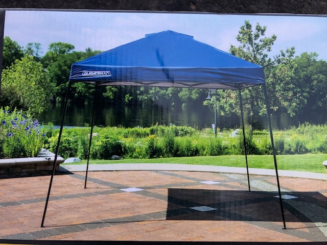Blue pop-up canopy for outdoor shade, perfect for RV rental camping trips. Provides portable shelter on a sunny patio by the water.